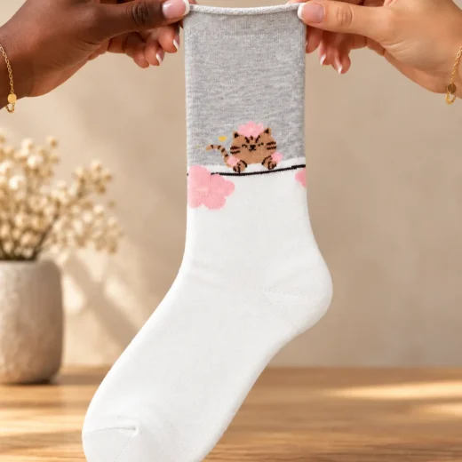 White and grey socks with cat and pink flower — held in hands