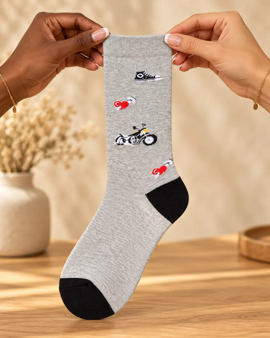 Calcetines gris claro con motos y detalles negros — sostenido con las manos