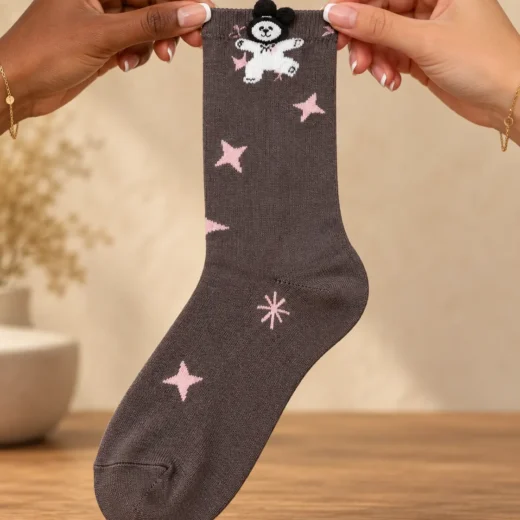 Taupe socks with teddy bear and pink stars — held in hands