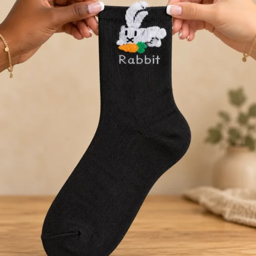 Black socks with white rabbit and raised ear — held in hands