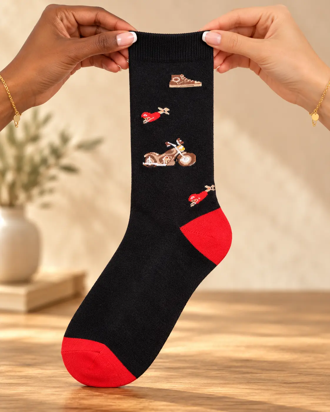 Calcetines negros con motos y detalles rojos — sostenido con las manos