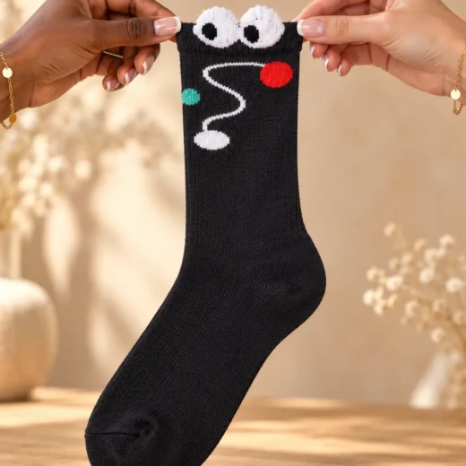 Black socks with eyes and colourful planets — held in hands